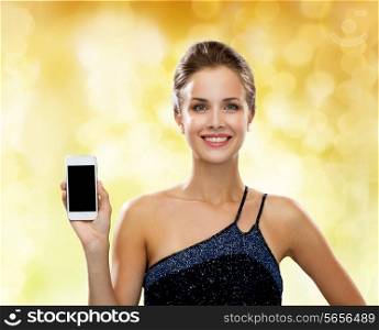 technology, communication, advertisement and people concept - smiling woman in evening dress holding smartphone over yellow holidays lights background