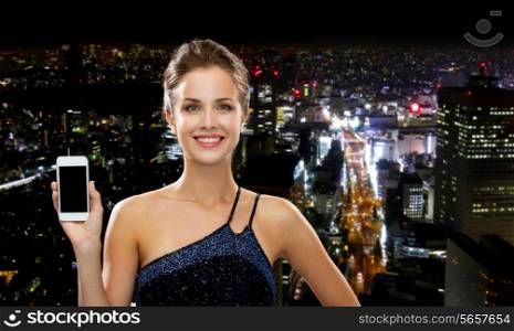 technology, communication, advertising and people concept - smiling woman in evening dress holding smartphone over night city background
