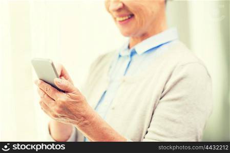 technology, communication, age and people concept - close up of happy senior woman with smartphone texting message at home