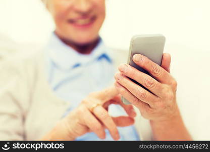 technology, communication age and people concept - close up of happy senior woman with smartphone texting message at home