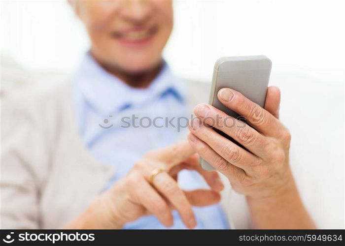technology, communication age and people concept - close up of happy senior woman with smartphone texting message at home