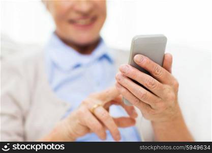 technology, communication age and people concept - close up of happy senior woman with smartphone texting message at home