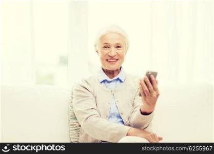 technology, communication age and people concept - happy senior woman with smartphone at home