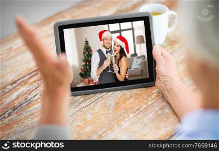 technology, communication and christmas holidays concept - senior woman having video call with her family on tablet computer at home. old woman has video call with family on christmas