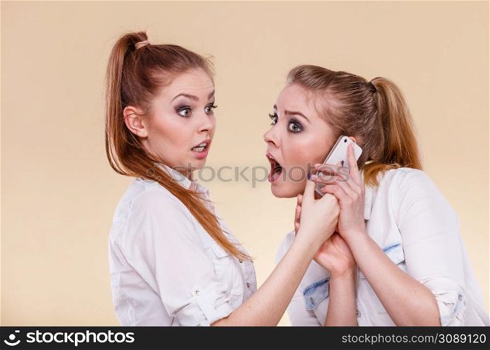 Technology communication and friendship concept. Funny teen girls using mobile phone talking, having fun, surprised emotional face expression. Girls using mobile phone talking