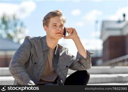 technology, communication and lifestyle concept - young man or teenage boy calling on smartphone in city. teenage boy calling on smartphone in city