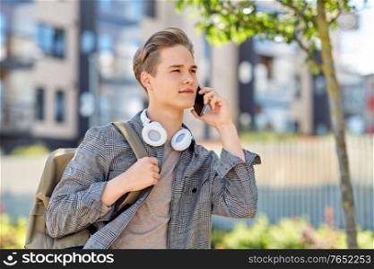 technology, communication and lifestyle concept - young man or teenage student boy with backpack calling on smartphone on city street. teenage student boy calling on smartphone in city