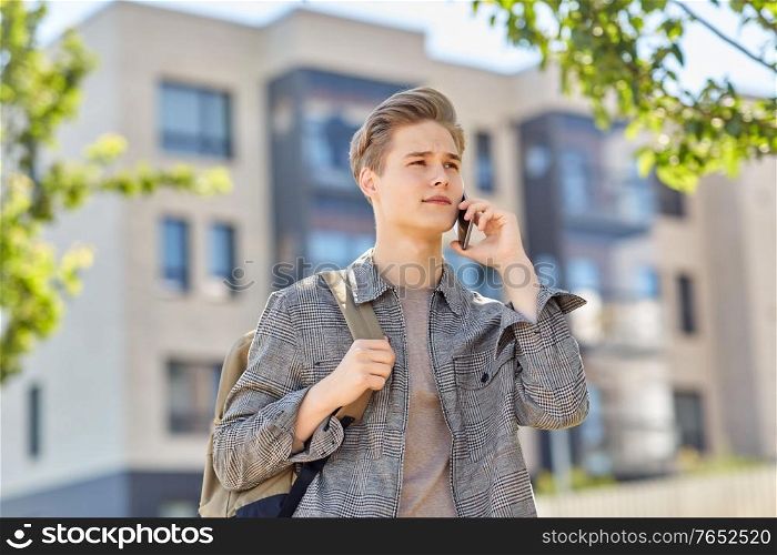 technology, communication and lifestyle concept - young man or teenage student boy with backpack calling on smartphone on city street. teenage student boy calling on smartphone in city