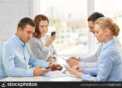 technology, communication and people concept - business team using smartphones at office. business team using smartphones at office