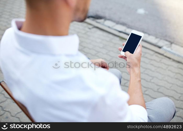 technology, communication and people concept - close up of man texting message on smartphone in city