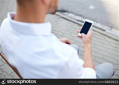 technology, communication and people concept - close up of man texting message on smartphone in city