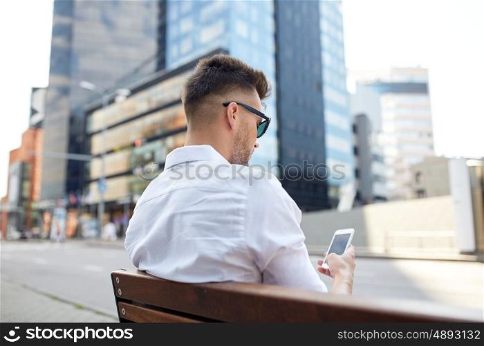 technology, communication and people concept - close up of man texting message on smartphone in city