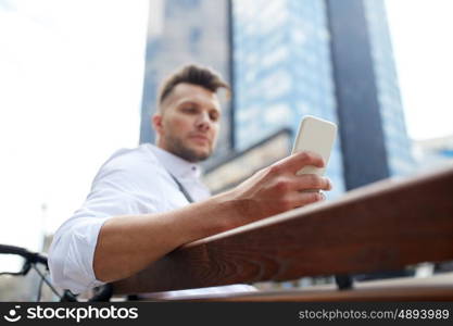 technology, communication and people concept - close up of man texting message on smartphone in city