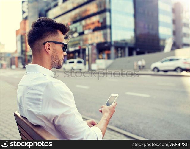 technology, communication and people concept - close up of man texting message on smartphone in city. close up of man texting on smartphone in city