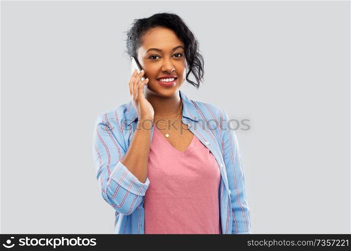 technology, communication and people concept - happy african american woman calling on smartphone over grey background. happy african american woman calling on smartphone