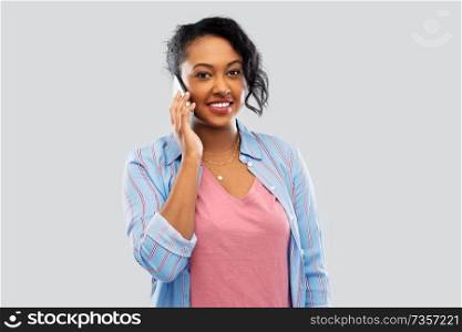 technology, communication and people concept - happy african american woman calling on smartphone over grey background. happy african american woman calling on smartphone
