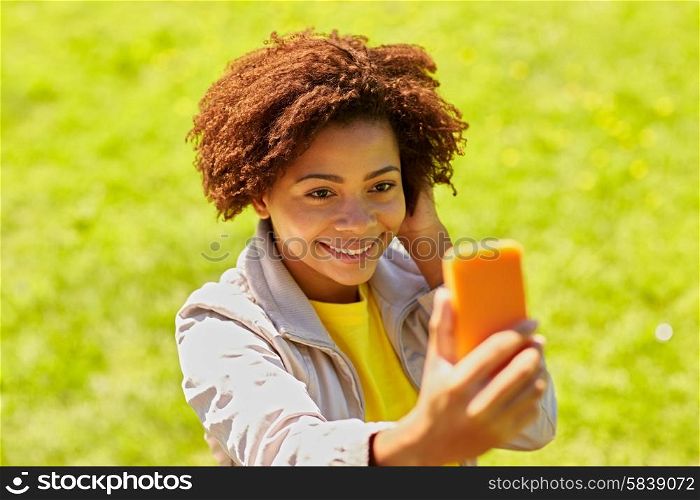 technology, communication and people concept - happy african woman taking selfie with smartphone at summer park