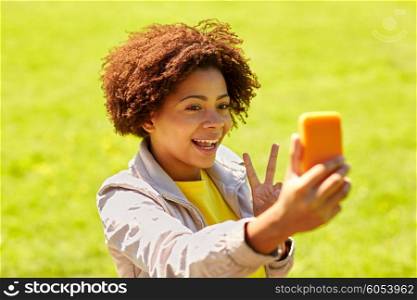 technology, communication and people concept - happy african woman taking selfie with smartphone at summer park