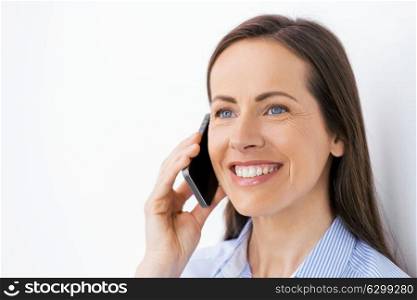 technology, communication and people concept - happy businesswoman calling on smartphone at office. businesswoman calling on smartphone at office