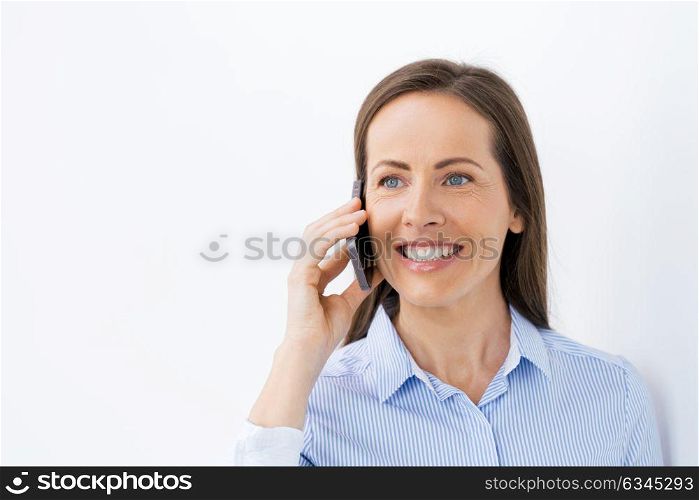 technology, communication and people concept - happy businesswoman calling on smartphone at office. businesswoman calling on smartphone at office