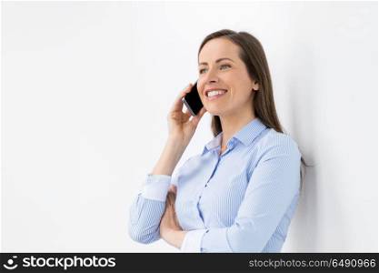 technology, communication and people concept - happy businesswoman calling on smartphone at office. businesswoman calling on smartphone at office. businesswoman calling on smartphone at office