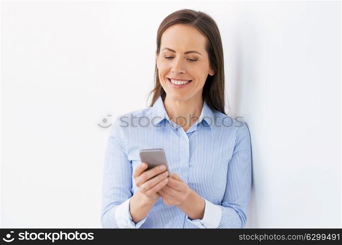 technology, communication and people concept - happy businesswoman with smartphone at office. businesswoman with smartphone at office