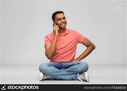 technology, communication and people concept - happy indian man calling on smartphone over grey background. happy indian man calling on smartphone