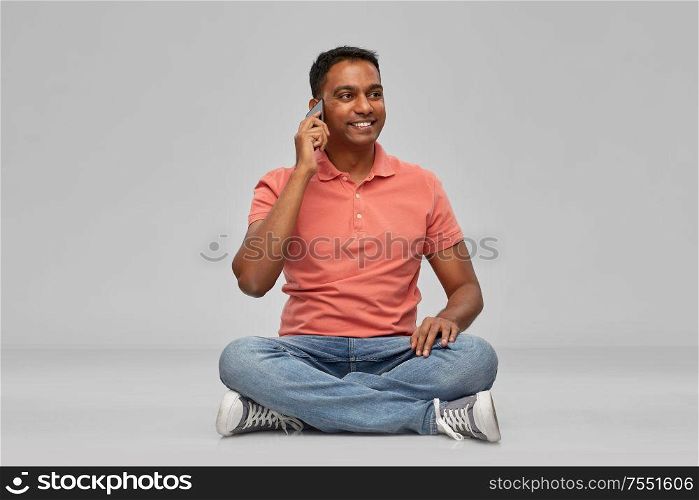 technology, communication and people concept - happy indian man calling on smartphone over grey background. happy indian man calling on smartphone