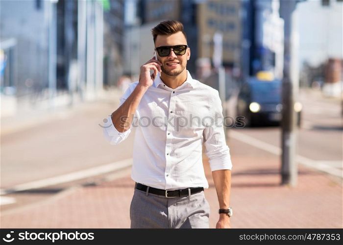 technology, communication and people concept - happy man with smartphone calling on city street