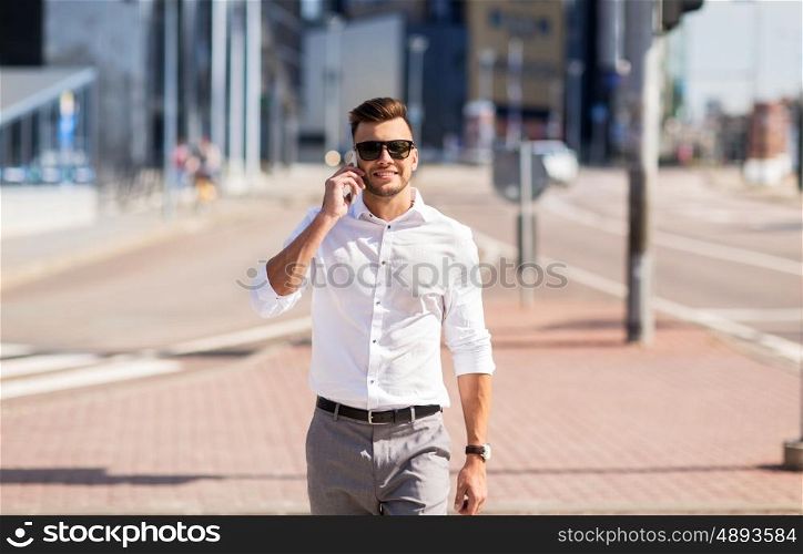 technology, communication and people concept - happy man with smartphone calling on city street