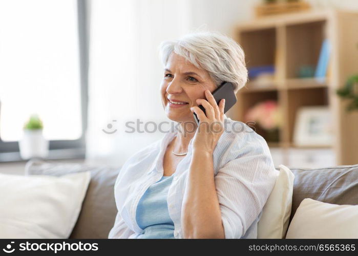 technology, communication and people concept - happy senior woman calling on smartphone at home. senior woman calling on smartphone at home