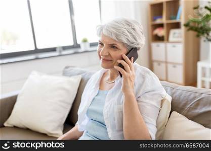 technology, communication and people concept - happy senior woman calling on smartphone at home. senior woman calling on smartphone at home