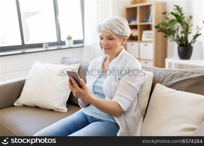 technology, communication and people concept - happy senior woman with smartphone at home. happy senior woman with smartphone at home