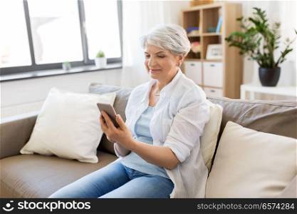 technology, communication and people concept - happy senior woman with smartphone at home. happy senior woman with smartphone at home