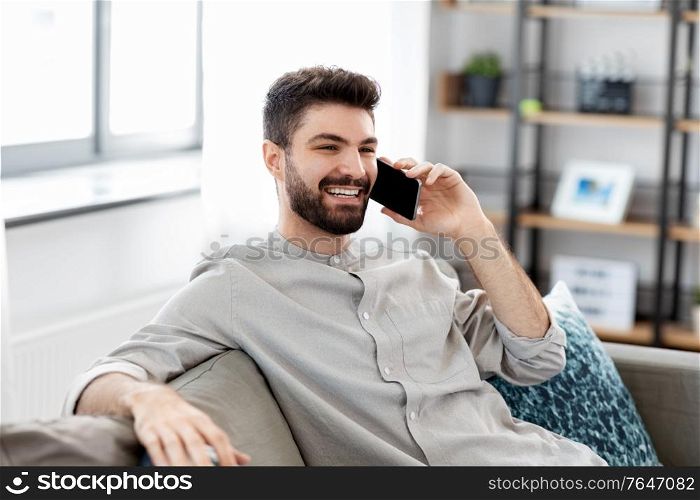 technology, communication and people concept - happy smiling man calling on smartphone at home. happy man calling on smartphone at home