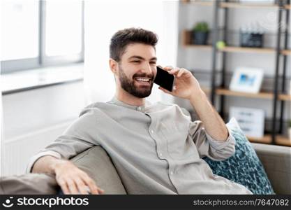 technology, communication and people concept - happy smiling man calling on smartphone at home. happy man calling on smartphone at home