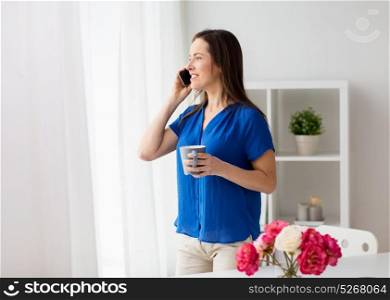 technology, communication and people concept - happy woman calling on smartphone and drinking coffee at office or home. woman calling on smartphone at office or home