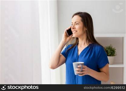 technology, communication and people concept - happy woman calling on smartphone and drinking coffee at office or home. woman calling on smartphone at office or home