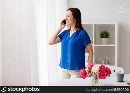 technology, communication and people concept - happy woman calling on smartphone at office or home. woman calling on smartphone at office or home