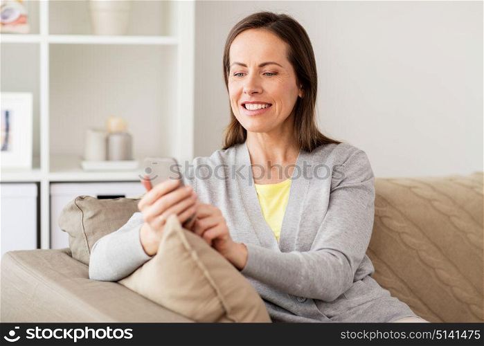 technology, communication and people concept - happy woman texting message on smartphone at home. happy woman texting message on smartphone at home