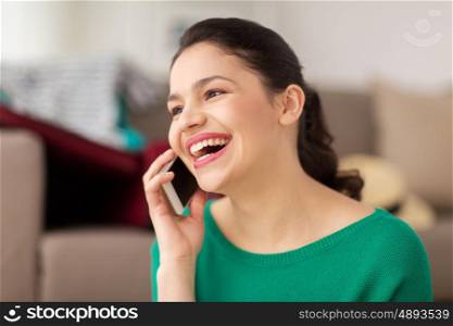 technology, communication and people concept - happy young woman calling on smartphone and laughing at home