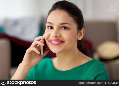 technology, communication and people concept - happy young woman calling on smartphone at home