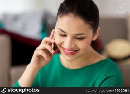 technology, communication and people concept - happy young woman calling on smartphone at home
