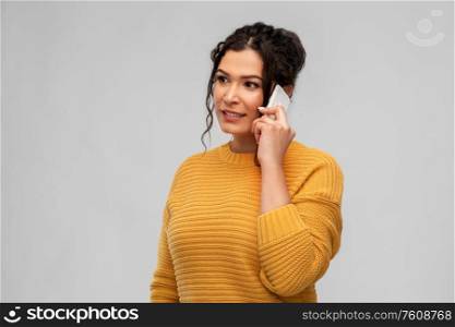 technology, communication and people concept - happy young woman calling on smartphone over grey background. happy young woman calling on smartphone
