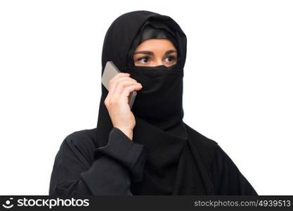 technology, communication and people concept - muslim woman in hijab calling on smartphone over white background. muslim woman in hijab over white background
