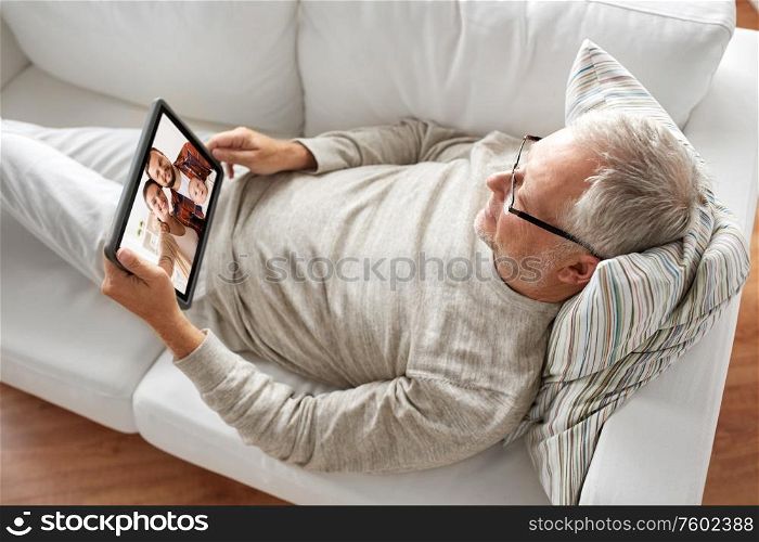 technology, communication and people concept - senior man having video call with happy family on tablet computer at home. senoir man having video call with family