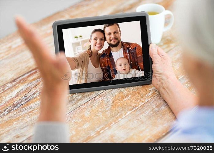 technology, communication and people concept - senior woman having video call with happy family on tablet computer at home. family having video call on tablet computer