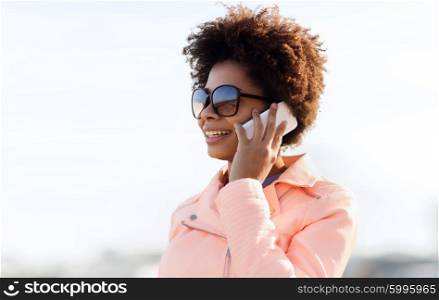 technology, communication and people concept - smiling african american young woman or teenage girl calling on smartphone outdoors