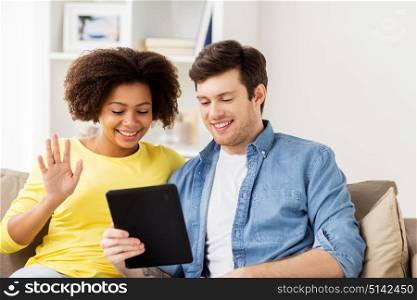technology, communication and people concept - smiling happy couple with tablet pc computer having video chat at home. smiling happy couple with tablet pc at home