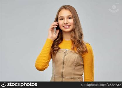 technology, communication and people concept - smiling teenage girl calling on smartphone over grey background. smiling teenage girl calling on smartphone